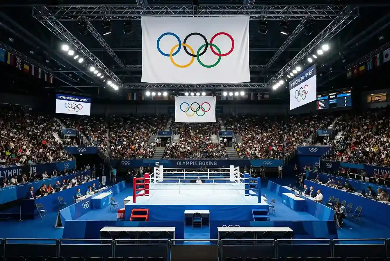 Ring de boxeo olimpico con los cinco aros olimpicos visibles en el fondo del pabellon