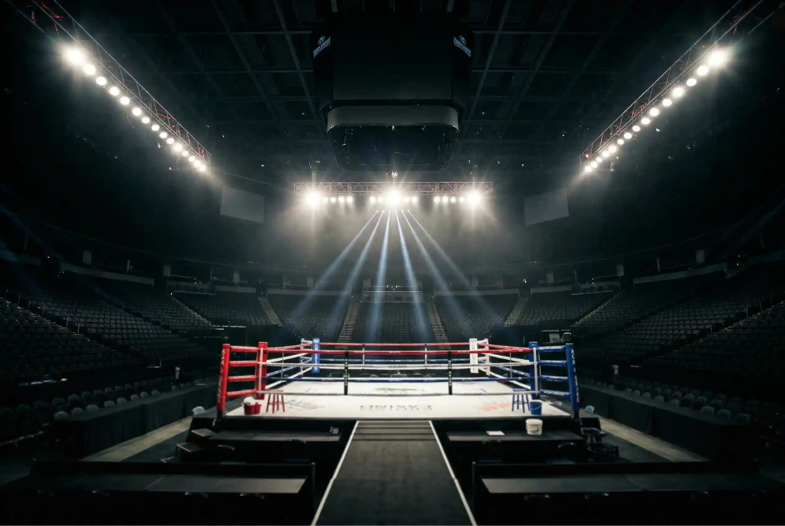Ring de boxeo iluminado con focos antes del inicio de un combate profesional
